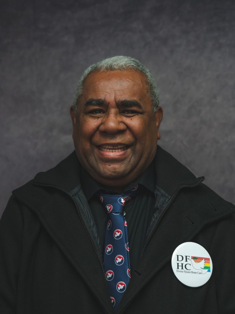 A smiling Divine Fijians Home Care team member wearing the DFHC pin.