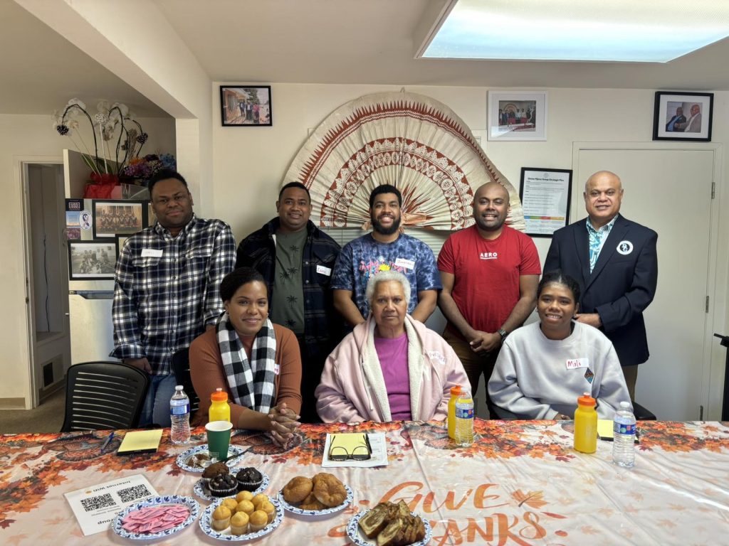 The Divine Fijians Home Care team gathered at a caregiver orientation beneath a traditional Fijian fan.